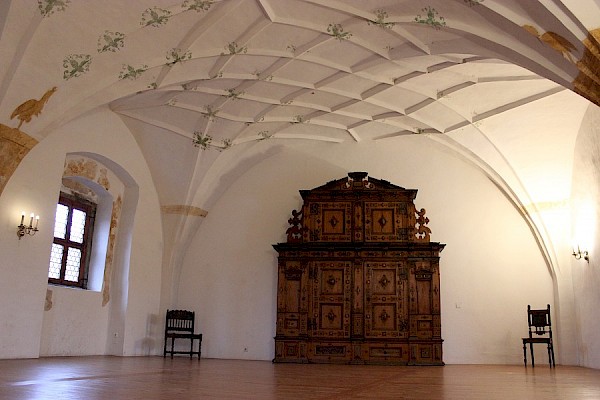 Der Vogelsaal - Blick in einen Saal mit hoher, gewölber Decke. An der Wand steht ein großer historischer Fassadenschrank.